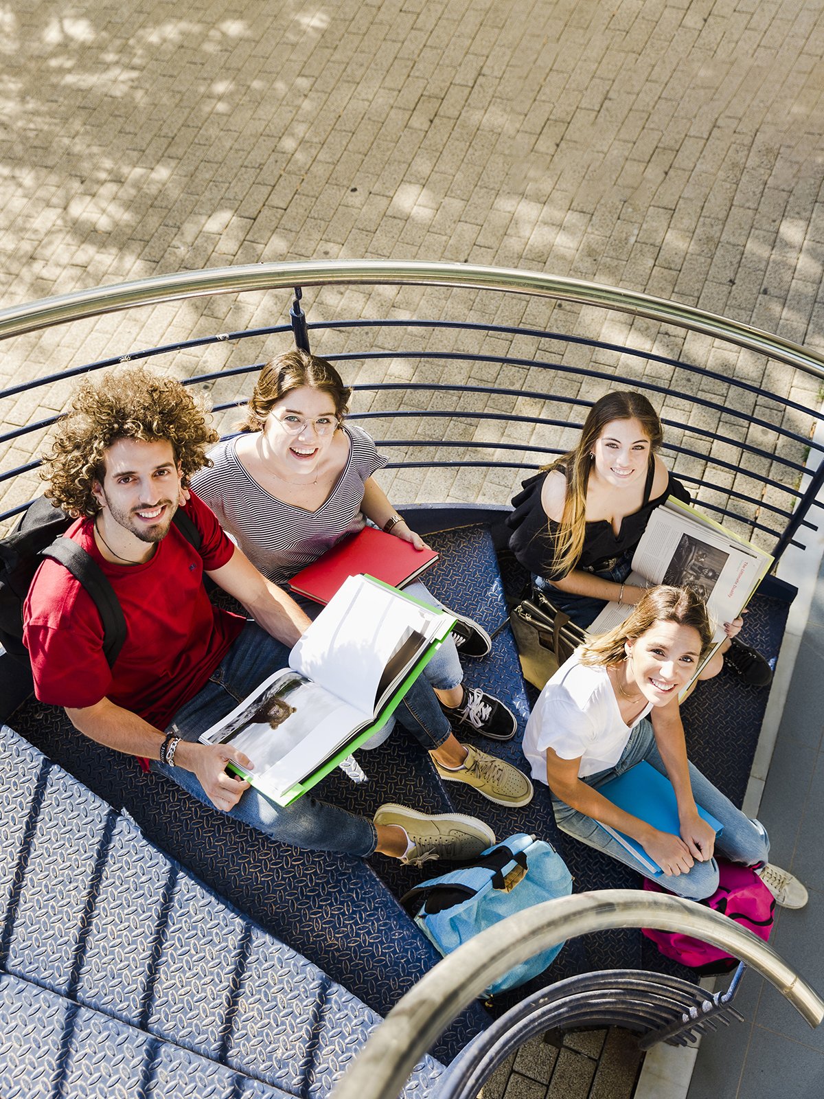 Groupe d'étudiants assis sur un escalier de campus avec leurs livres